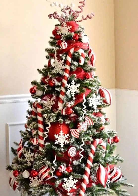 a bright and chic Christmas tree with candy canes, red ornaments, snowflakes, twigs and berries is amazing