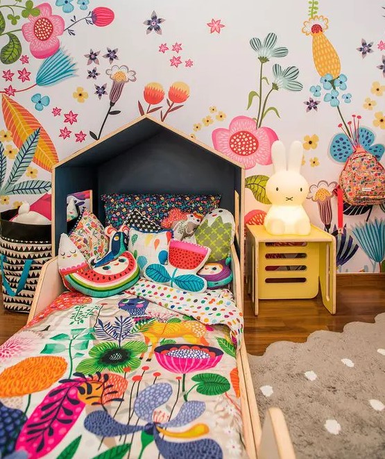 a bright and fun kid's room with a floral wall, matching floral bedding, fruit and flower pillows and a Miffy lamp