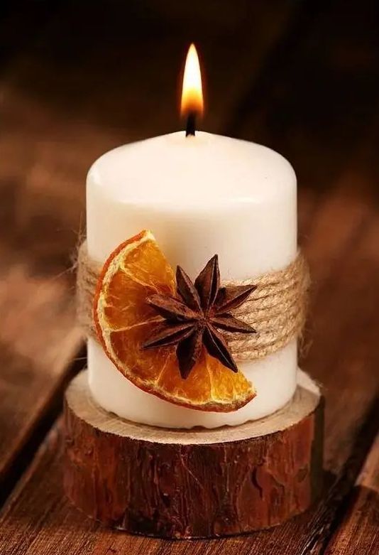 a candle with twine, a dried fruit slice and a spice piece is a gorgeous idea for fall or winter and it provides cool aroma