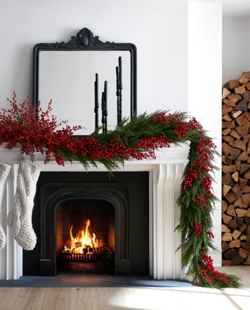 a chic Christmas fireplace with a mantel decorated with evergreens and red berries, with white stockings is a lovely idea
