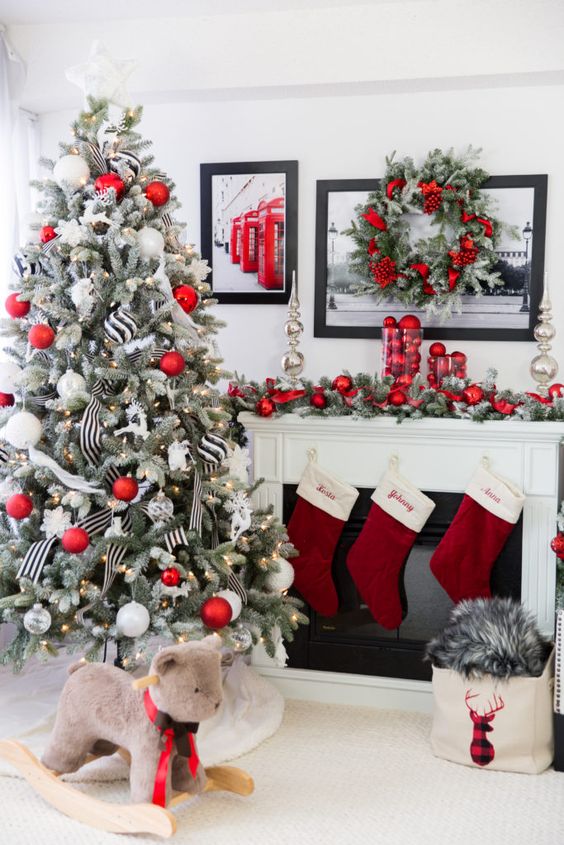 a chic Christmas space with red stockings, a Christmas tree decorated with silver, white and red ornaments, red ornaments on the mantel and in the wreath