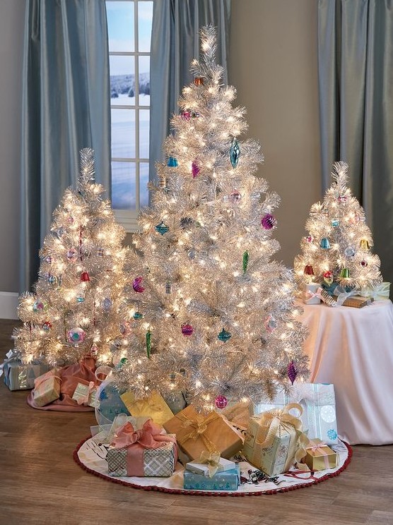 a cluster or silver Christmas trees decorated with colorful ornaments and lights, with stacks of gift boxes for refined holiday decor