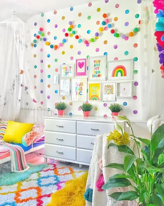 a colorful kid's space with a polka dot wall, a bold garland, bright bedding and fruit pillows and a bold rug just wows
