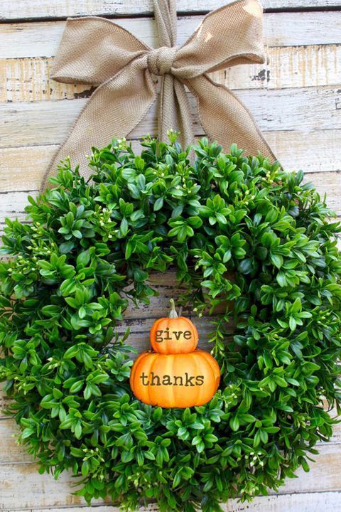 a cool and fresh Thanksgiving wreath of boxwood and little pumpkins and a large burlap bow for your front door