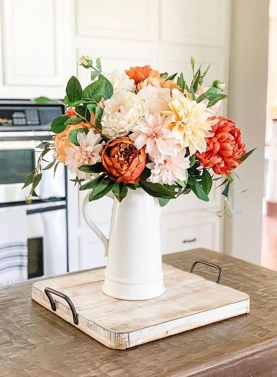 a cool floral Thanksgiving centerpiece of blush, peachy and orange blooms plus greenery is a simple and lovely idea