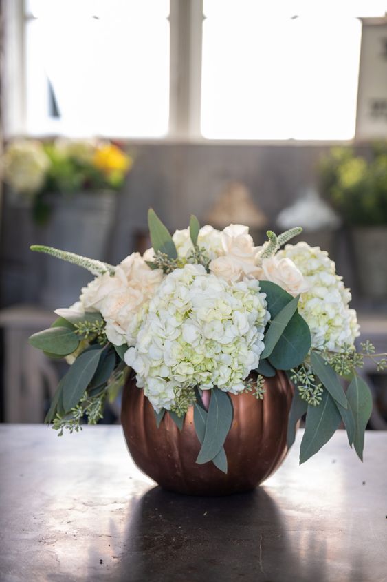 a copper pumpkin with white and blush blooms plus euclayptus is a cool Thanksgiving centerpiece