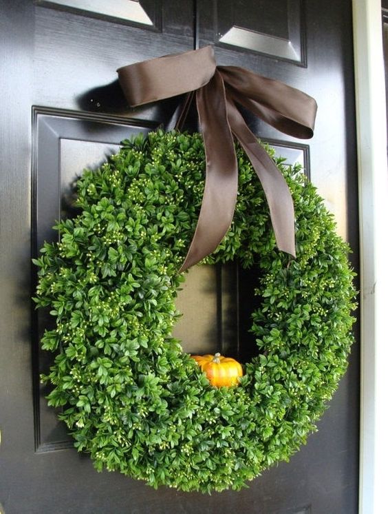 a cute fall or Thanksgiving wreath of fake greenery, a little faux pumpkin and a brown silk ribbon bow