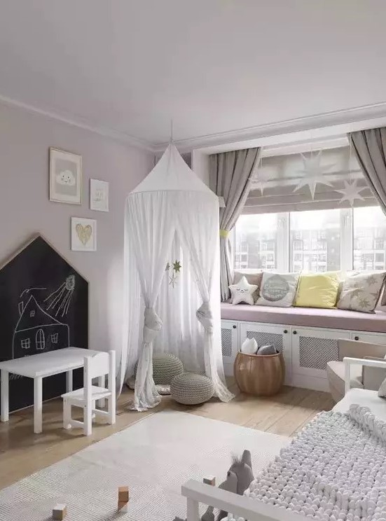 a delicate and subtle Scandi nursery with blush walls, a large windowsill bench with pillows, a bed with neutral bedding and a teepee