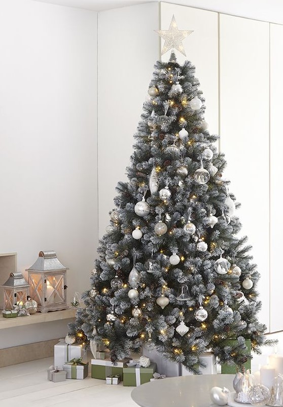 a delicate neutral Christmas tree decorated with white, silver and semi sheer ornaments, lights and a lit up star tree topper