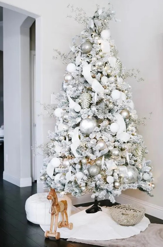 a dreamy flocked Christmas tree with silver and white ornaments, branches, ribbons and lights is an amazing idea