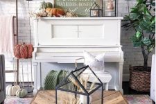a fall or Thanksgiving mantel with heirloom pumpkins, paper leaves and blooms, lanterns with wheat and some signs