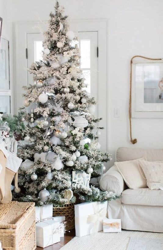 a flocked Christmas tree with white, silver and emerald ornaments, feathers, pinecones and grey ribbons is a lovely idea