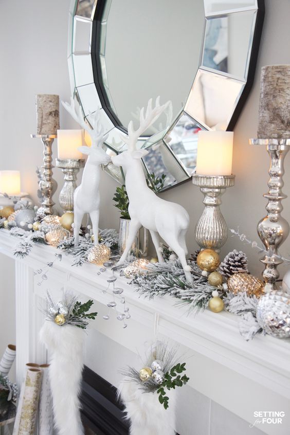 a glam Christmas mantel with snowy evergreens, gold and silver ornaments, white deer and some stockings