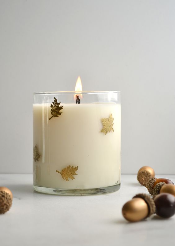 a glass candle with tiny gold leaves attached on the outside is a beautiful fall and Thanksgiving decor idea