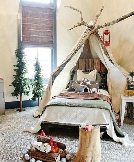 a gorgeous camp-themed kids' room with canopy on branches, woven shades, faux trees and a faux fireplace