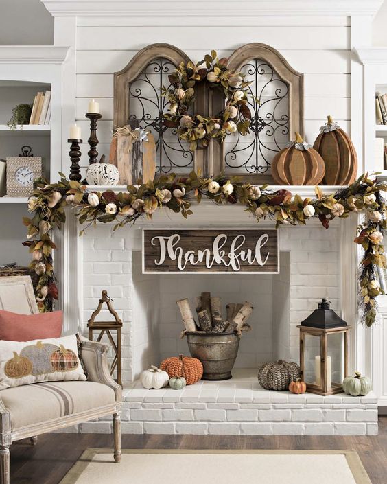 a gorgeous vintage Thanksgiving mantel with a lush dried leaf, pumpkin and wheat garland and wreath, wooden pumpkins and candles