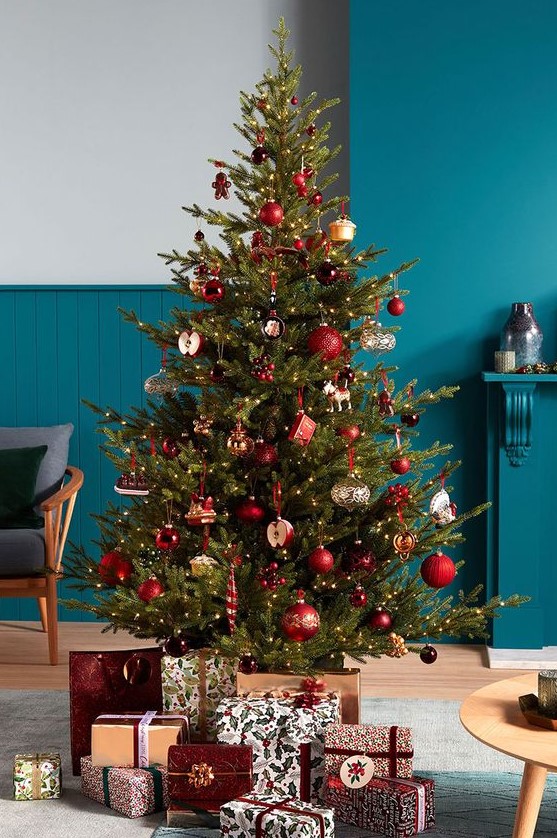 a green Christmas tree decorated with lovely red bauble ornaments and some whimsical like cupcakes and apples