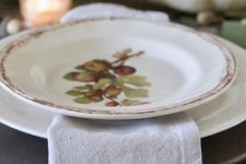 a grey wooden placemat, a white and a fruit printed plate plus a printed napkin are amazing for a cozy Thanksgiving tablescape