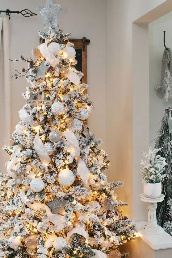 a jaw-dropping winter wonderland Christmas tree with white and silver ornaments, lights, ribbons, branches and pinecones is wow