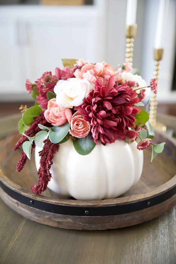 a lovely Thanksgiving centerpiece of a white pumpkin, white, blush and deep pink blooms and leaves is a fab idea