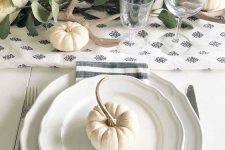 a lovely neutral Thanksgiving place setting with vintage plates, a striped napkin, silver and a small pumpkin on top is cool