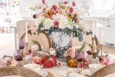 a lush and pretty Thanksgiving centerpiece of a refined urn, white, blush, pink and orange blooms and greenery plus colorful velvet pumpkins