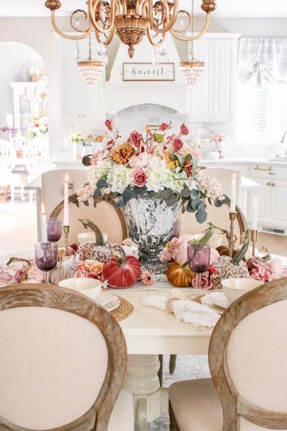 a lush and pretty Thanksgiving centerpiece of a refined urn, white, blush, pink and orange blooms and greenery plus colorful velvet pumpkins