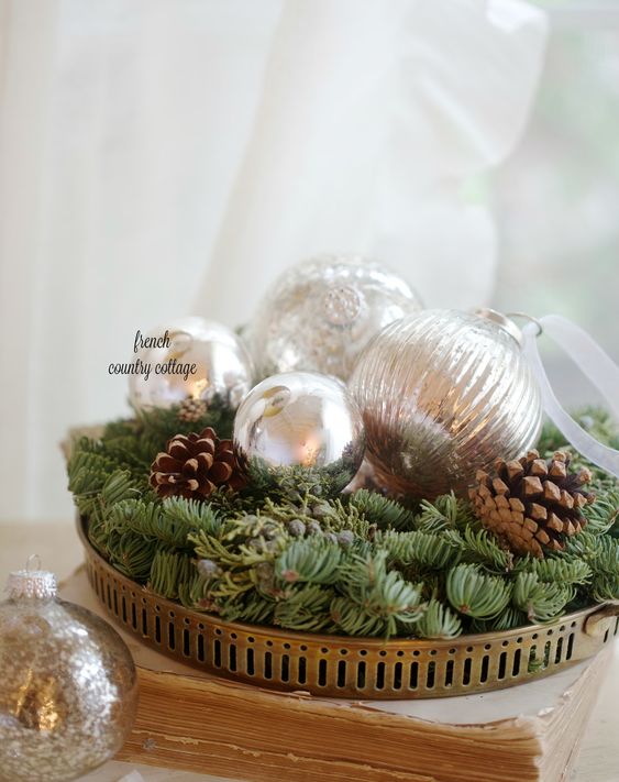 a metal tray with evergreens, silver ornaments and pinecones is a cool Christmas centerpiece idea