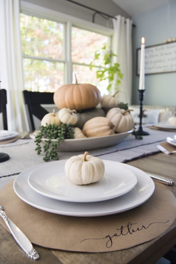 a natural Thanksgiving place setting with a cardboard placemat, elegant and simple porcelain and a mini white gourd is a cool idea