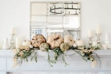 a neutral Thanksgiving mantel with greenery, white blooms, pumpkins and neutral candles is chic and beautiful
