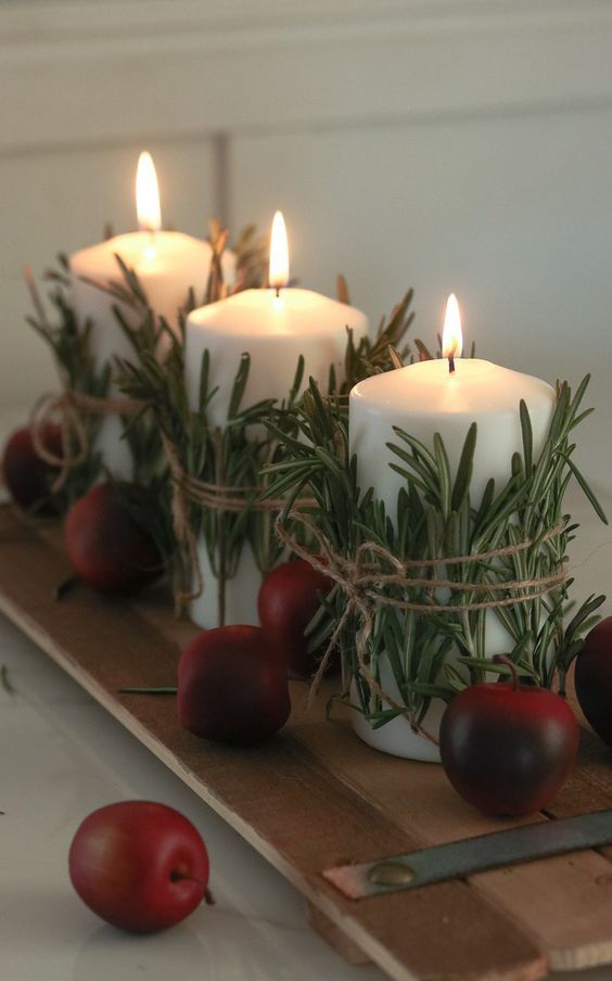 a planked board with candles wrapped with herbs and some faux apples is a great decor idea for fall and Thanksgiving
