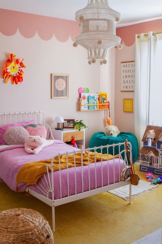 a pretty and bright kid's room with scallop edge walls, a bed with bold pink bedding, a green pouf and lovely rugs, books and toys