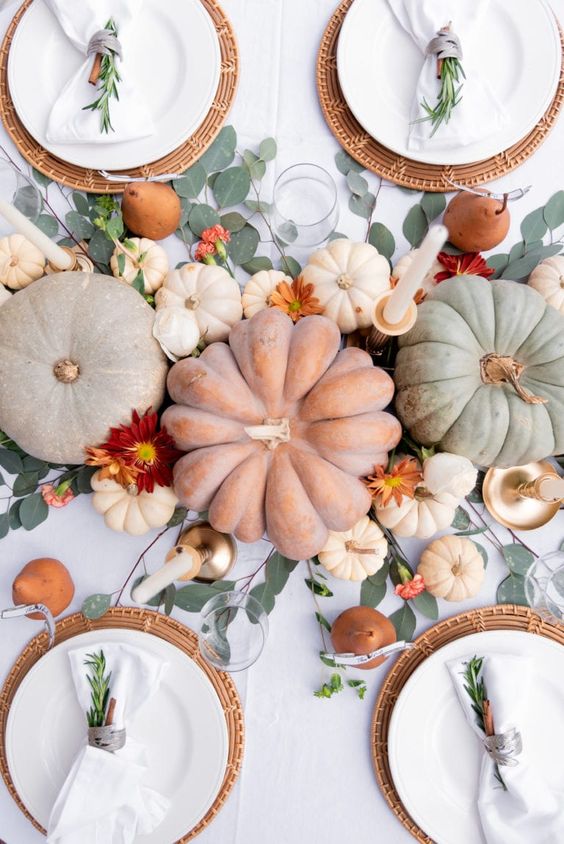 a pretty and natural Thanksgiving centerpiece of some pumpkins, small and large ones, bold blooms and tall and thin candles
