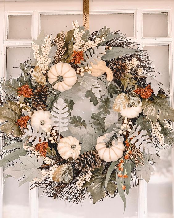 a pretty neutral textural fall or Thanksgiving wreath of pale leaves, white pumpkins, pinecones and twigs is a lovely idea