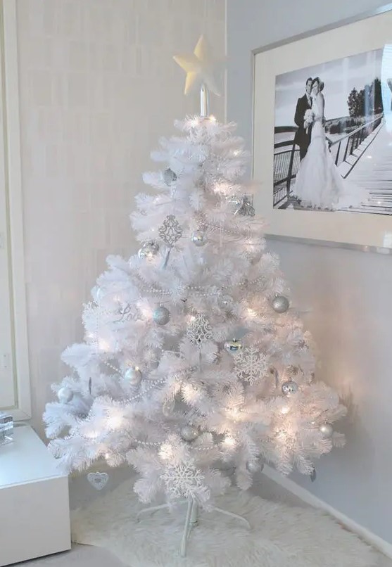 a pure white Christmas tree with lights and silver and white ornaments plus a star on top