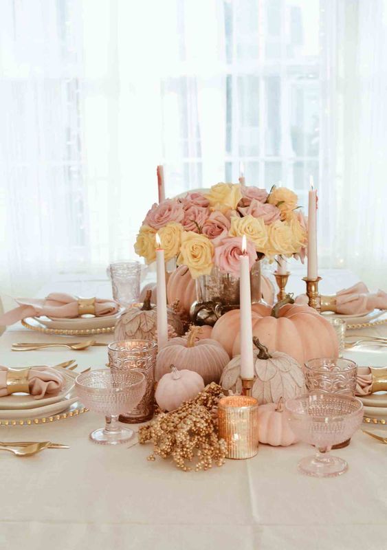 a refined pastel Thanksgiving centerpiece of blush natural and faux pumpkins, pink blooms, candles and some beads