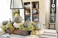 a rustic Thanksgiving centerpiece of a wooden box, green hydrangeas and neutral heirloom pumpkins is a cozy and cool idea