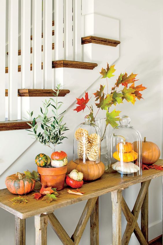 a rustic Thanksgiving console with bright leaves, pumpkins and gourds is a pretty decoration