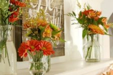 a rustic chic Thanksgiving mantel with bold blooms and greenery arrangements, a wooden sign and paper fall leaf garland