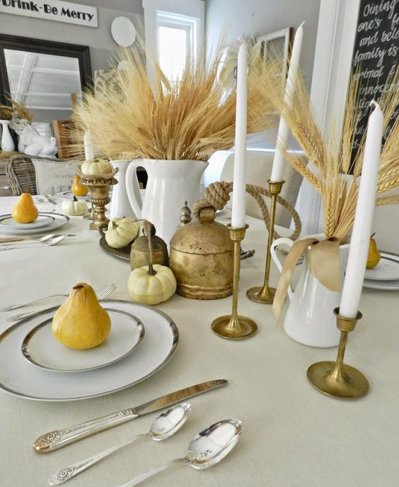 a rustic vintage cluster Thanksgiving centerpiece of wheat, candles, pumpkins and vintage brass touches is chic