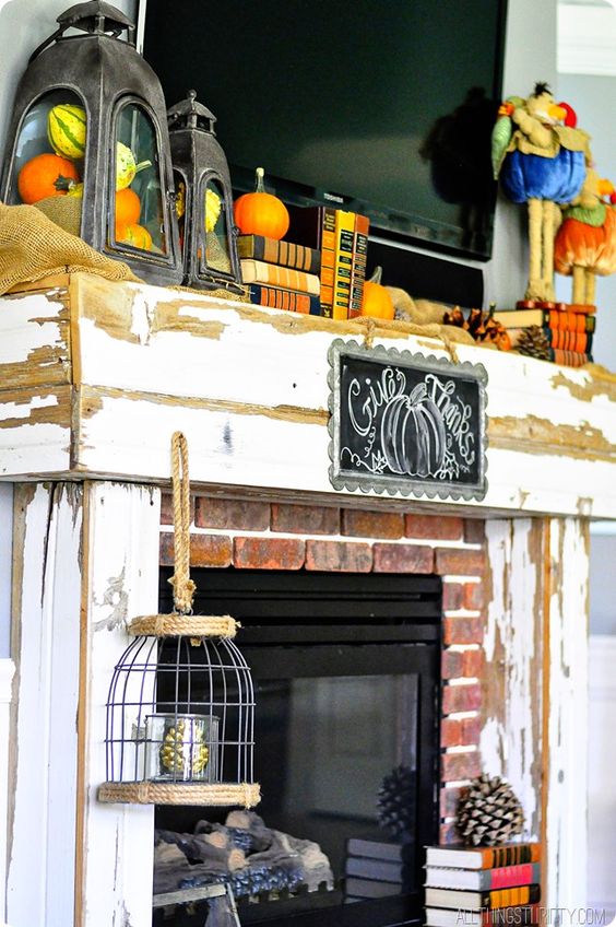 a shabby chic Thanksgiving mantel with lanterns with pumpkins, books, bold velvet pumpkins and pinecones