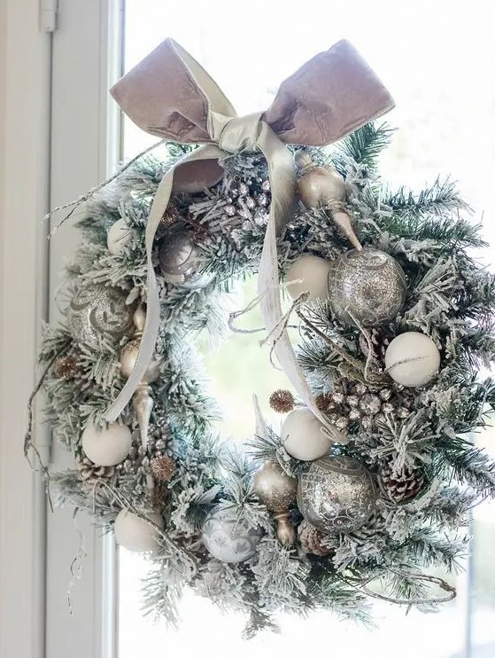 a silver Christmas wreath with snowy pinecones and a bow on top is a chic idea for Christmas decor