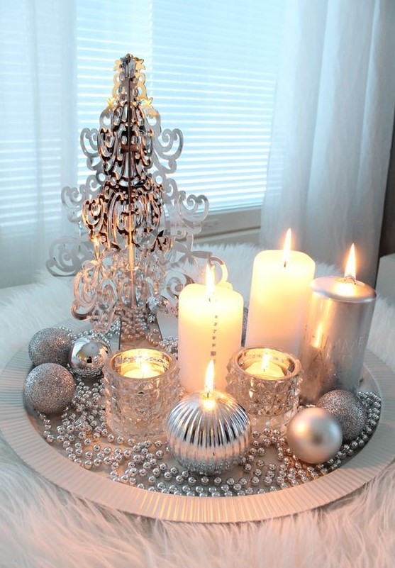 a silver tray with beads, a plastic tree, candles and silver ornaments for a glam space