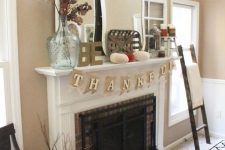 a simple Thanksgiving mantel with velvet pumpkins, oversized vintage mirrors, a dried leaf arrangement in a glass vase plus candles