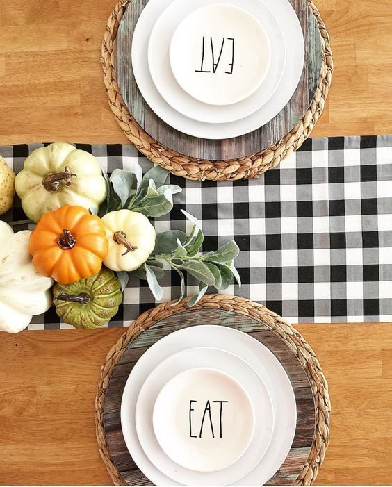 a simple modern farmhouse Thanksgiving tablescape with woven placemats, wooden chargers, white plates and printed ones on top is very chic