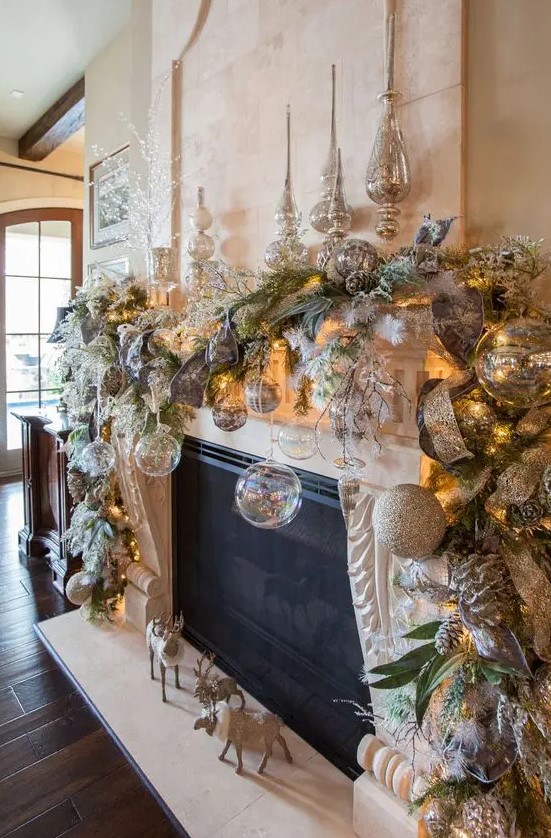 a sophisticated Christmas mantel with clear and silver glitter ornaments, snowy leaves and ribbons, white branches and lights