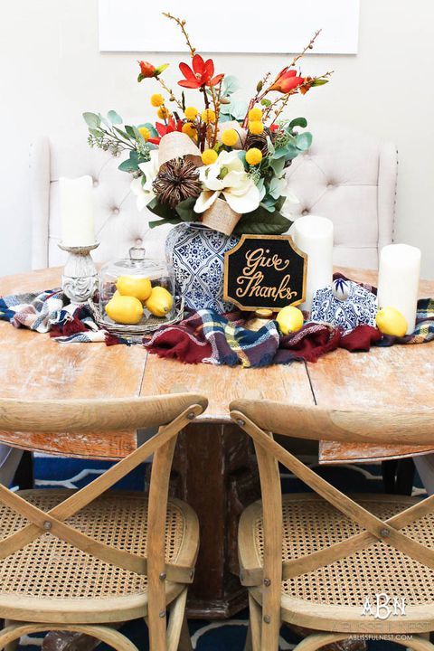 a super bold Thanksgiving centerpiece of white, red blooms, greenery, billy balls, a vine pumpkin and pillar candles