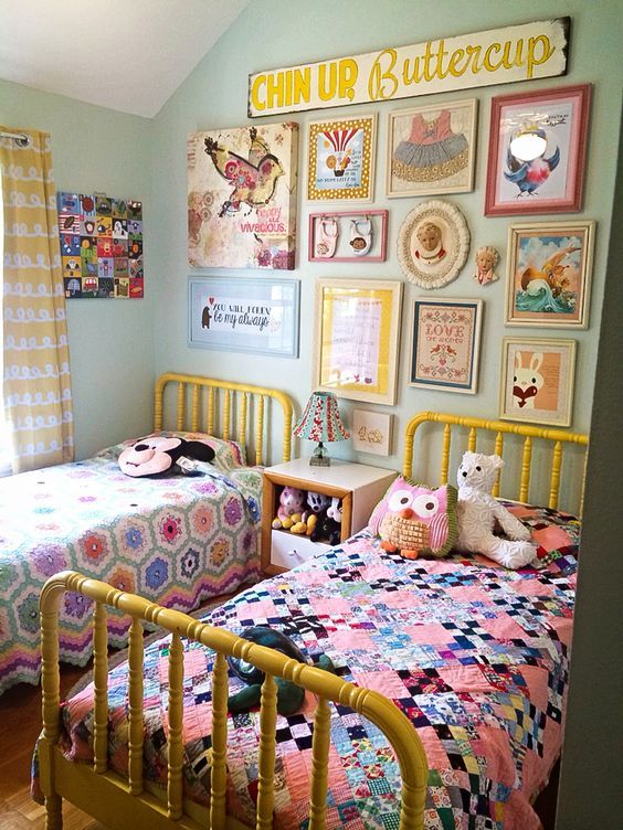 a super fun and bright shared kids' room with light green walls, yellow beds with colorful bedding, a bright gallery wall and toys