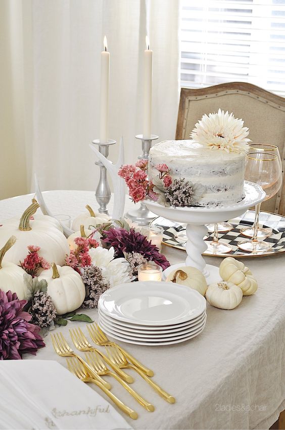 a super lush Thanksgiving centerpiece of white pumpkins, pink, white and purple blooms among them is a simple and cool idea