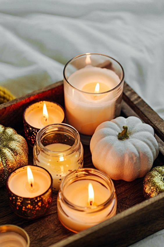 a tray with candles in jars and neutral and gold glitter pumpkins is a gorgeous and very easy decoration for Thanksgiving